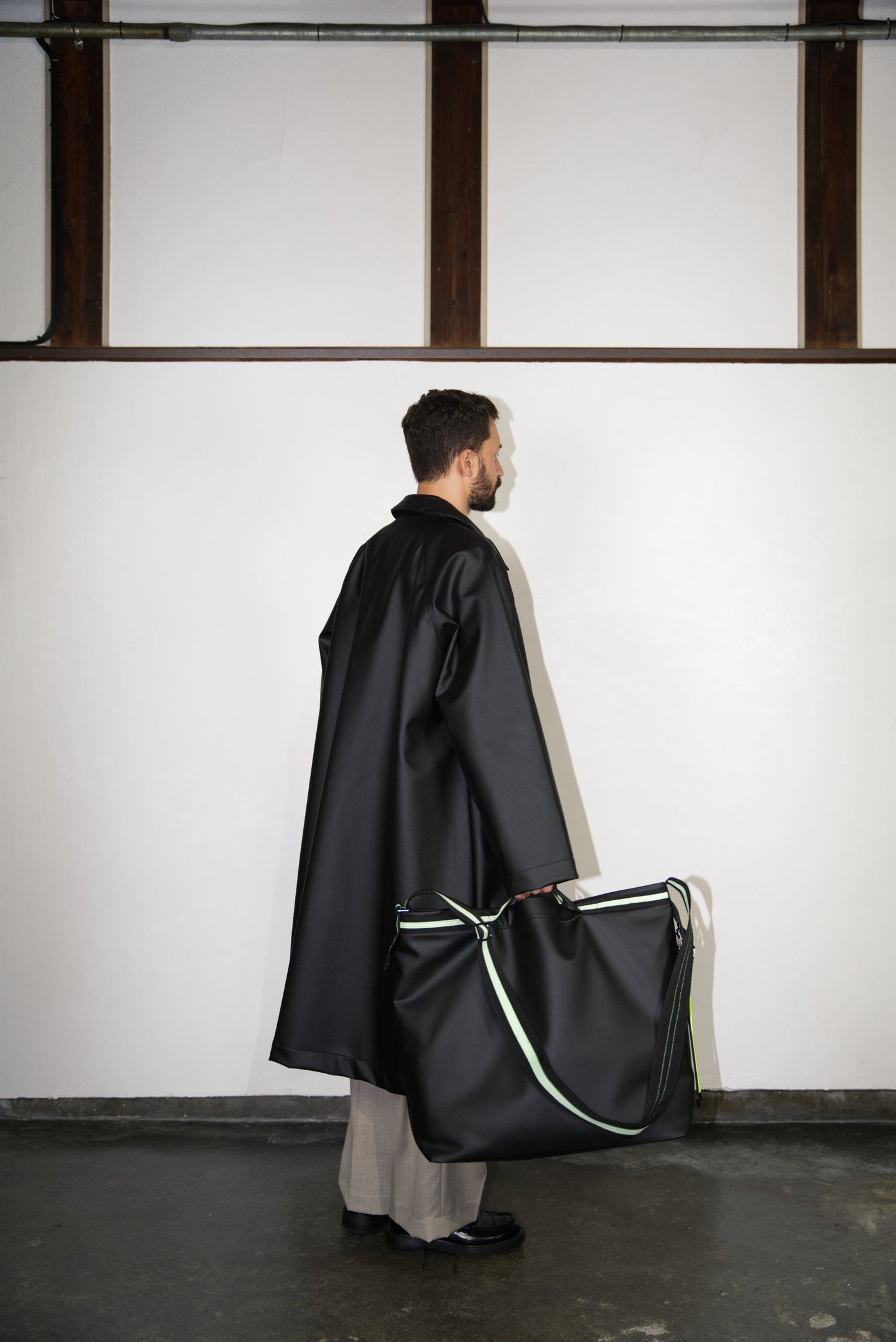 male model from the side holding the Large Helmet Bag in Cactus Leather in green