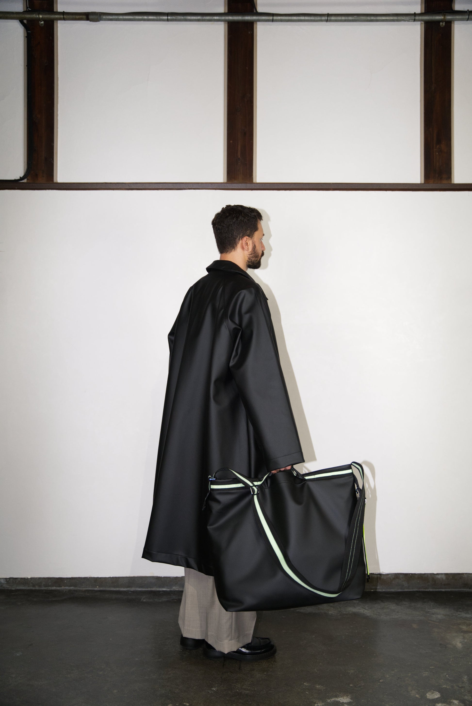 male model from the side holding the Large Helmet Bag in Cactus Leather in green