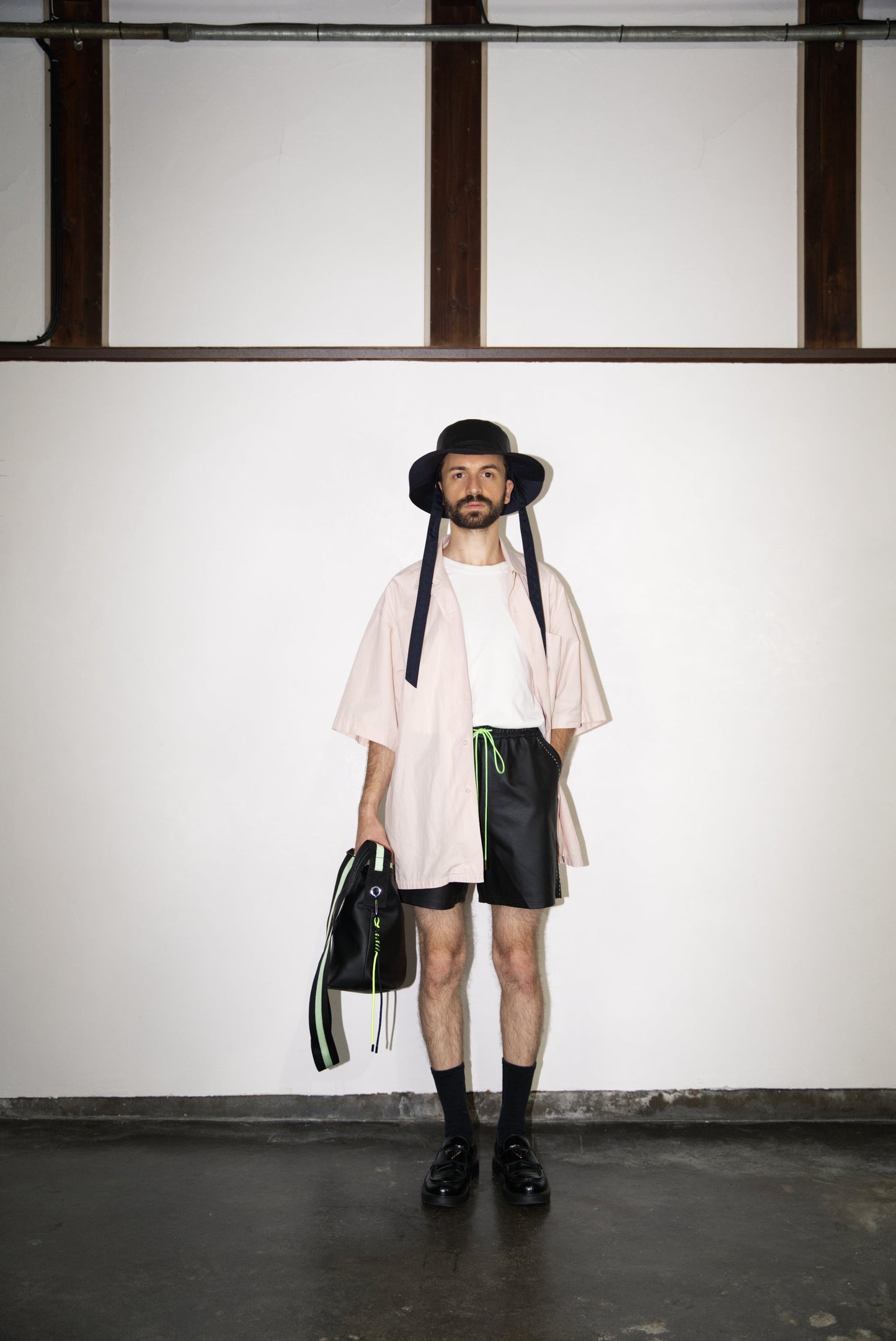 male model wearing the Hand-Stitched SCENE Cactus Leather Shorts in neon green with hat, bag and shirt