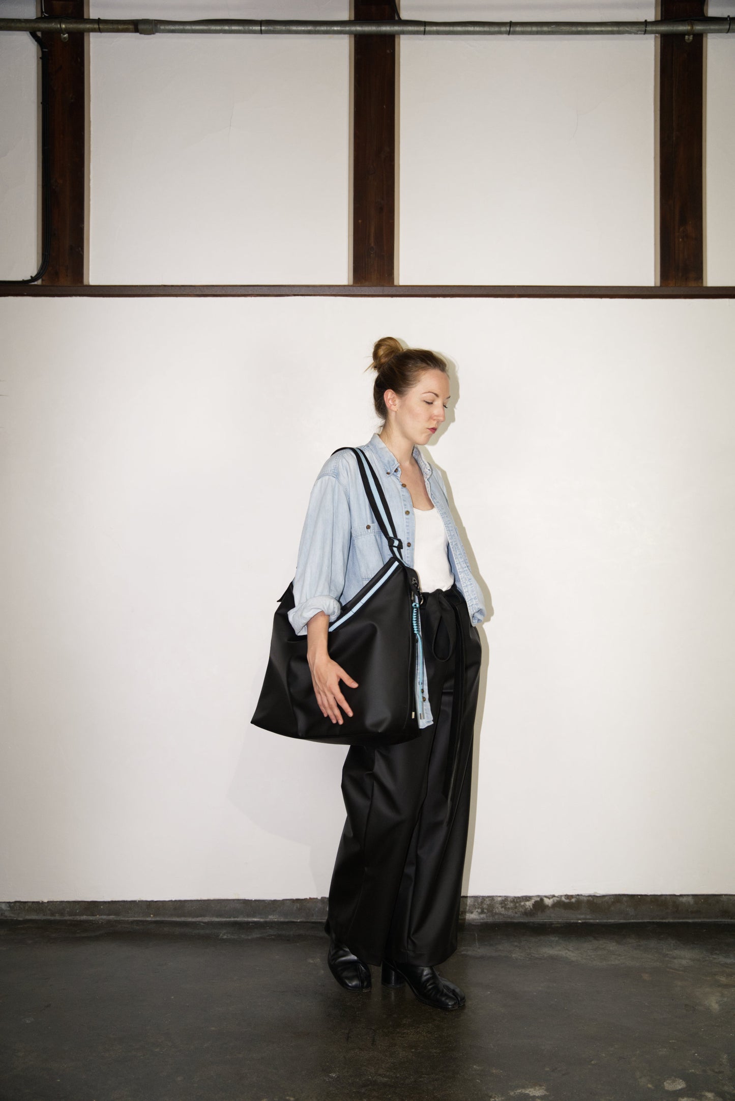 female model carrying the Large Helmet Bag in Cactus Leather in blue on her shoulder
