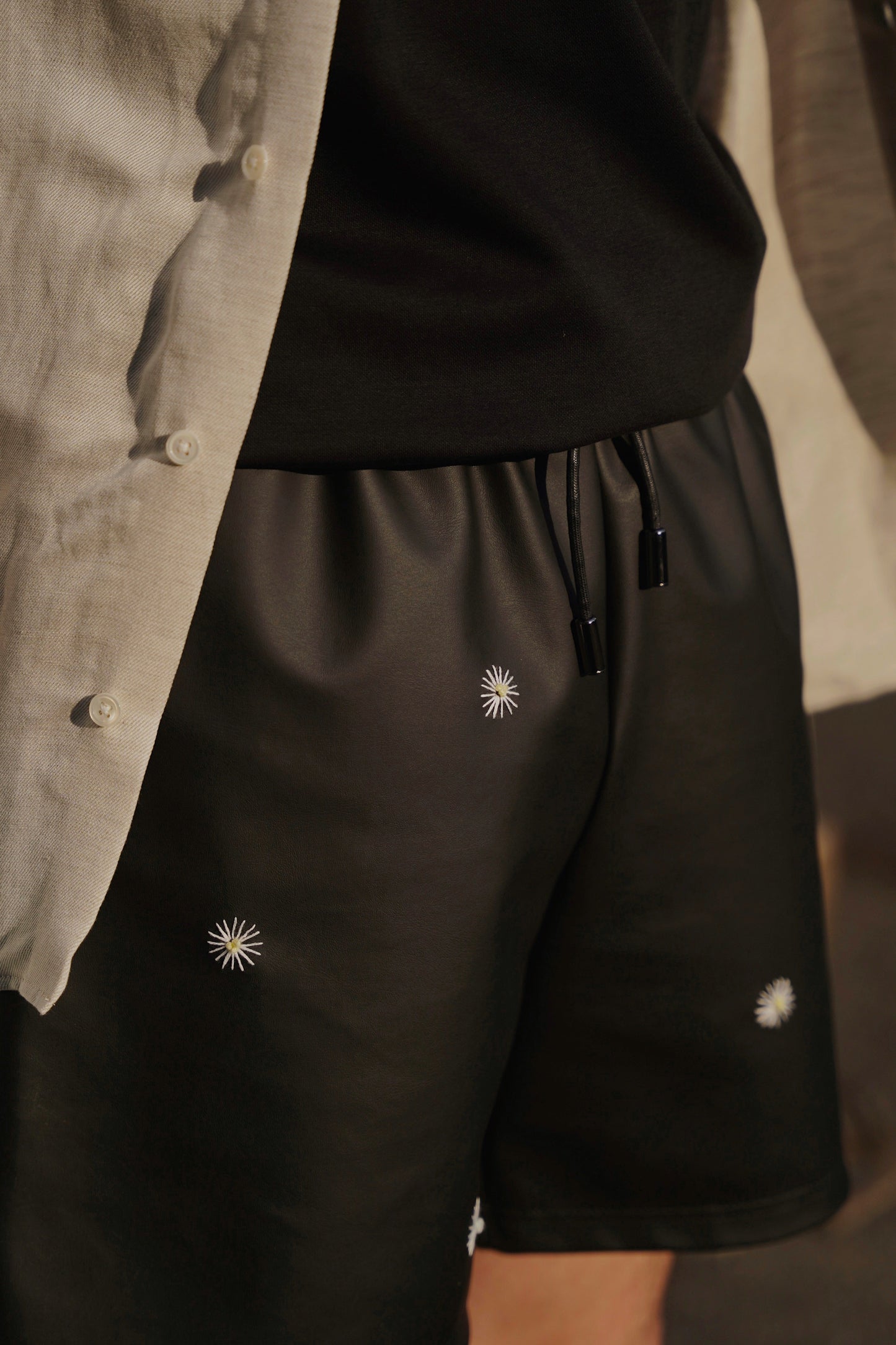 front side of hand-stitched scene cactus leather shorts in black on model