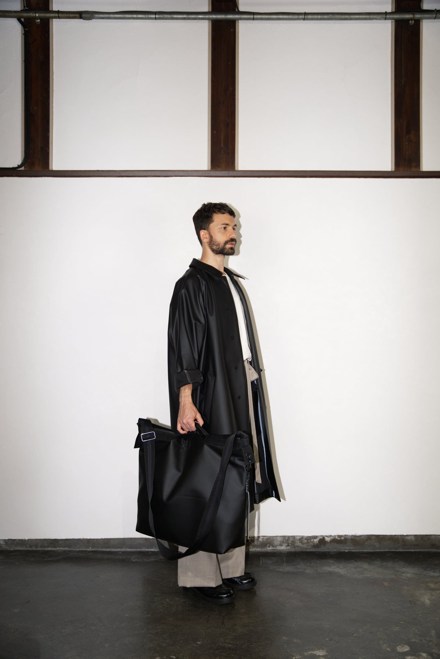 male model carrying the Large Helmet Bag in Cactus Leather in black
