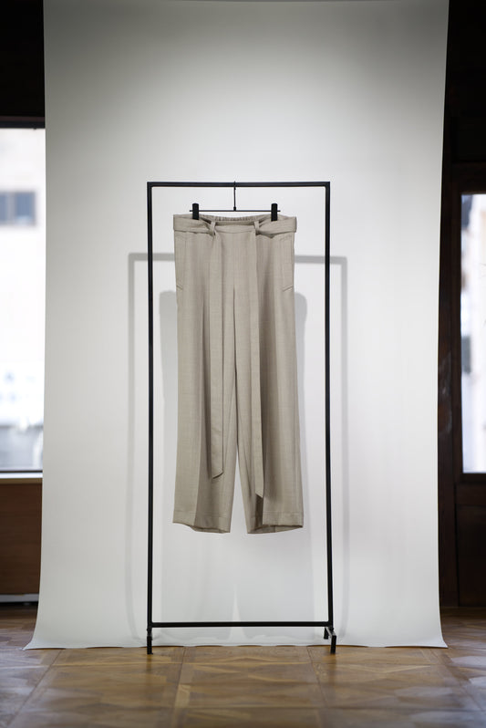 Belted Wide Flare Trousers in Wool hanging on a rack