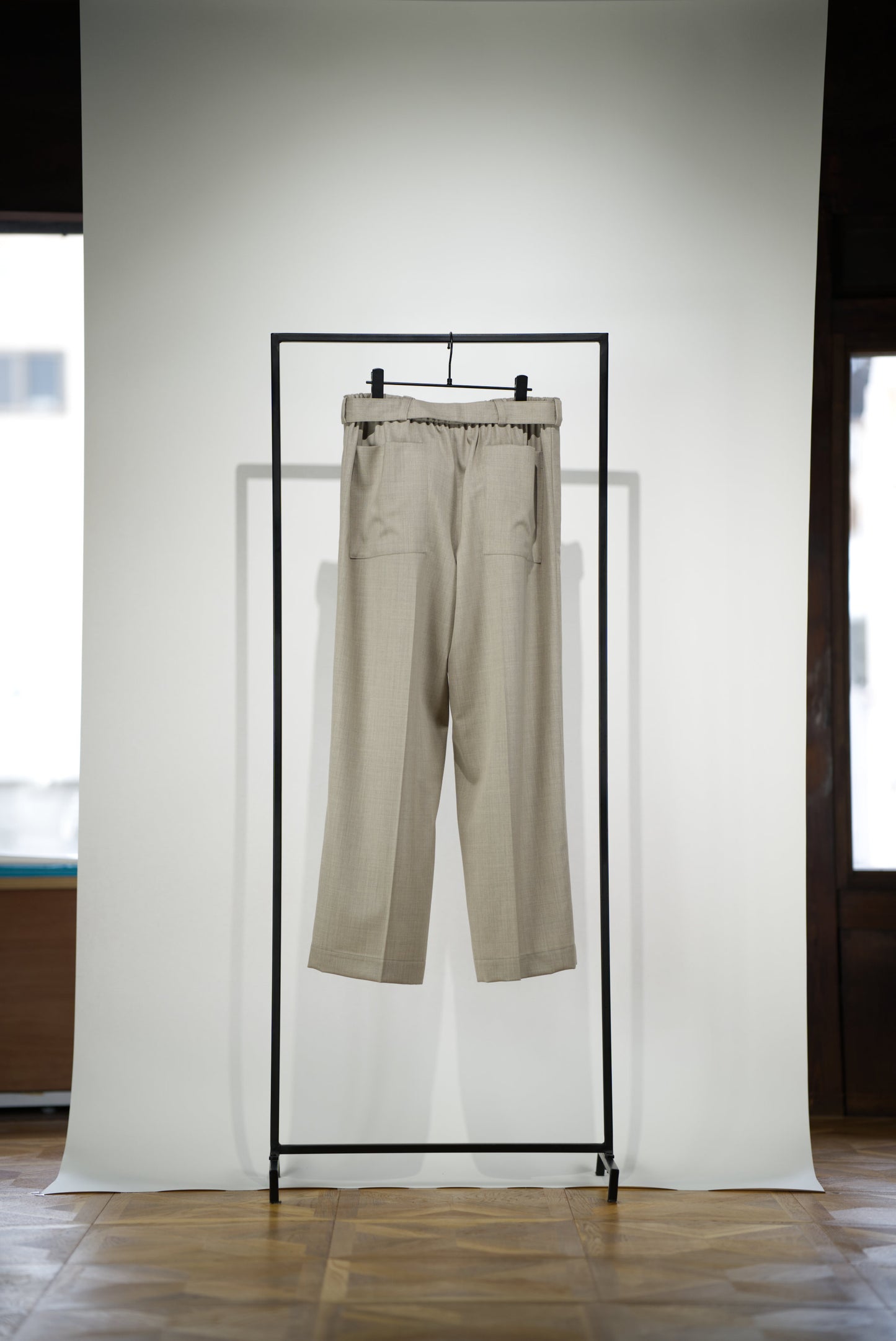 Belted Wide Flared Trousers in Wool back side hanging on a rack